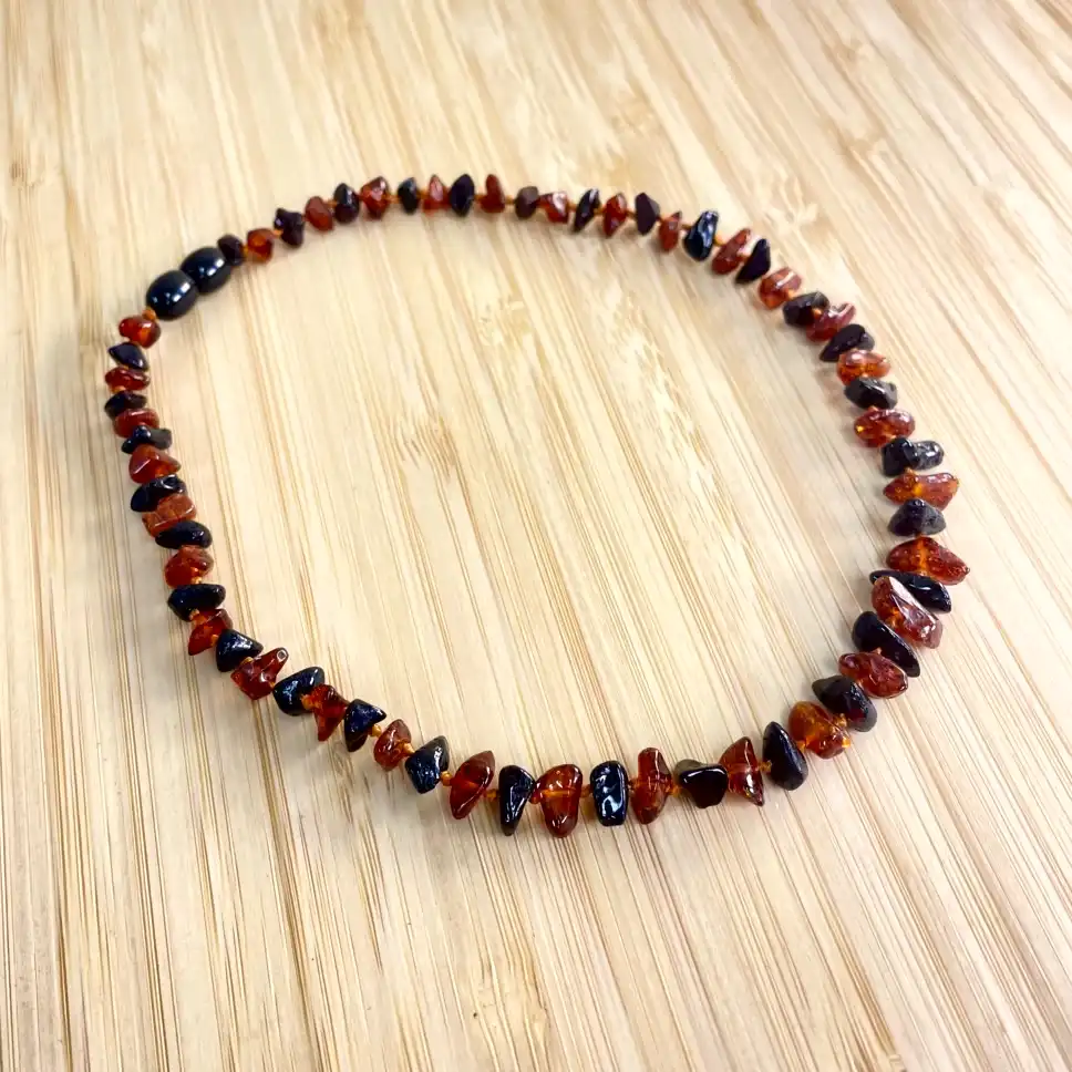 Elegant amber teething necklace with polished beads and black accents on a wooden background.
