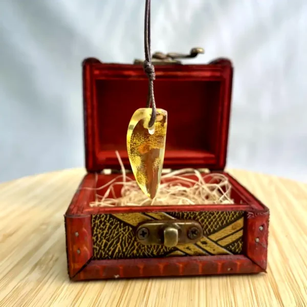 Elegant amber pendant on vintage chest, showcasing natural beauty and antique craftsmanship.