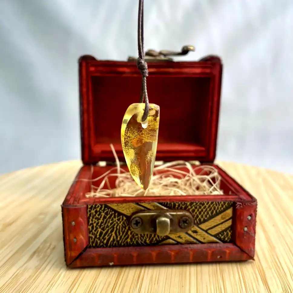 Elegant amber pendant on vintage chest, showcasing natural beauty and antique craftsmanship.