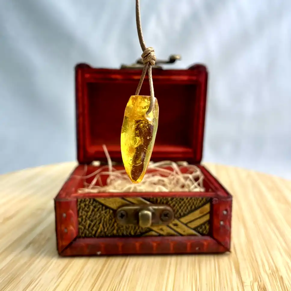 Amber pendant in ornate red box showcases natural beauty and artisanal craftsmanship.
