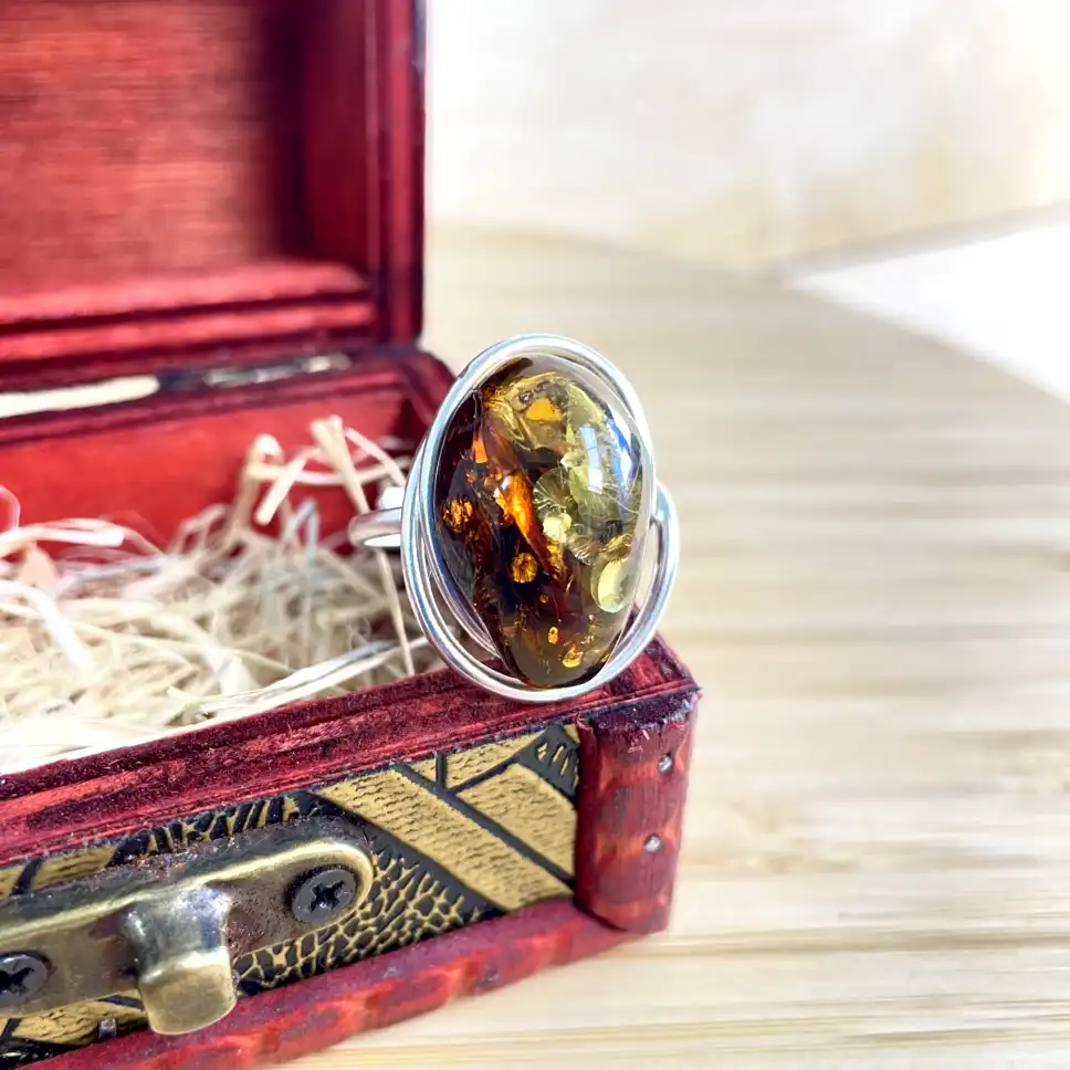 Exquisite silver-plated amber ring in a vintage red jewelry box, showcasing natural beauty and elegance.