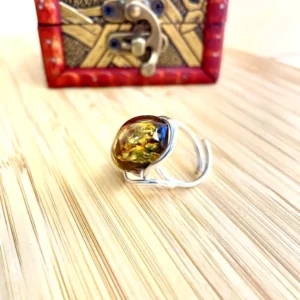 Stunning amber ring displayed on a wooden surface with decorative box in the background.
