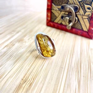 Elegant amber ring with silver band displayed on natural wood surface.