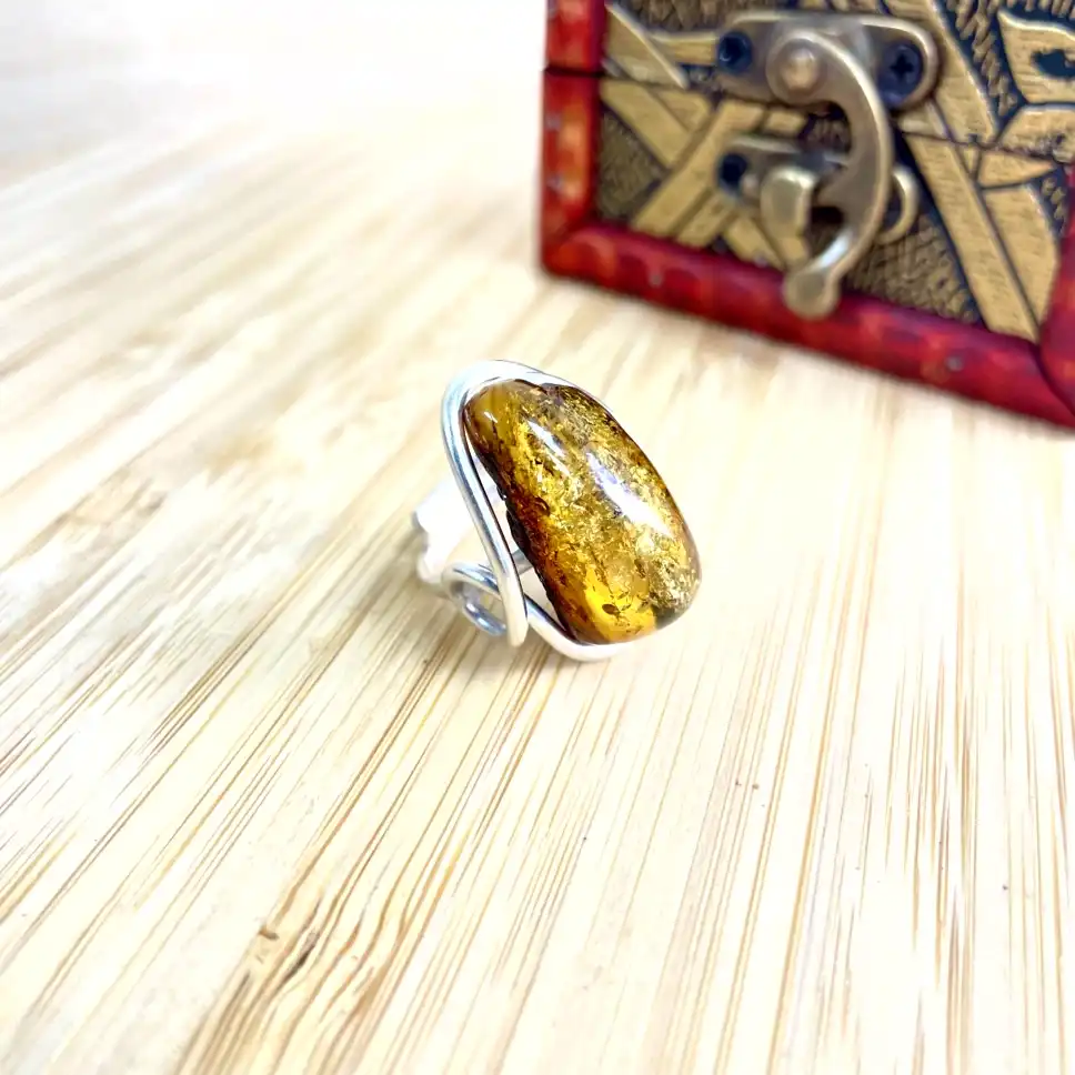 Stunning amber ring with silver-plated setting, beautifully presented on a wooden surface.