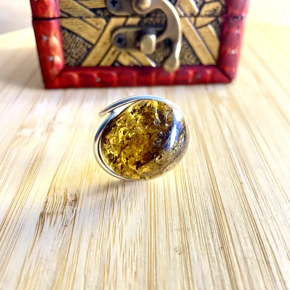 Stunning silver-plated amber ring in silver plating with natural patterns, showcased on a decorative wooden box.