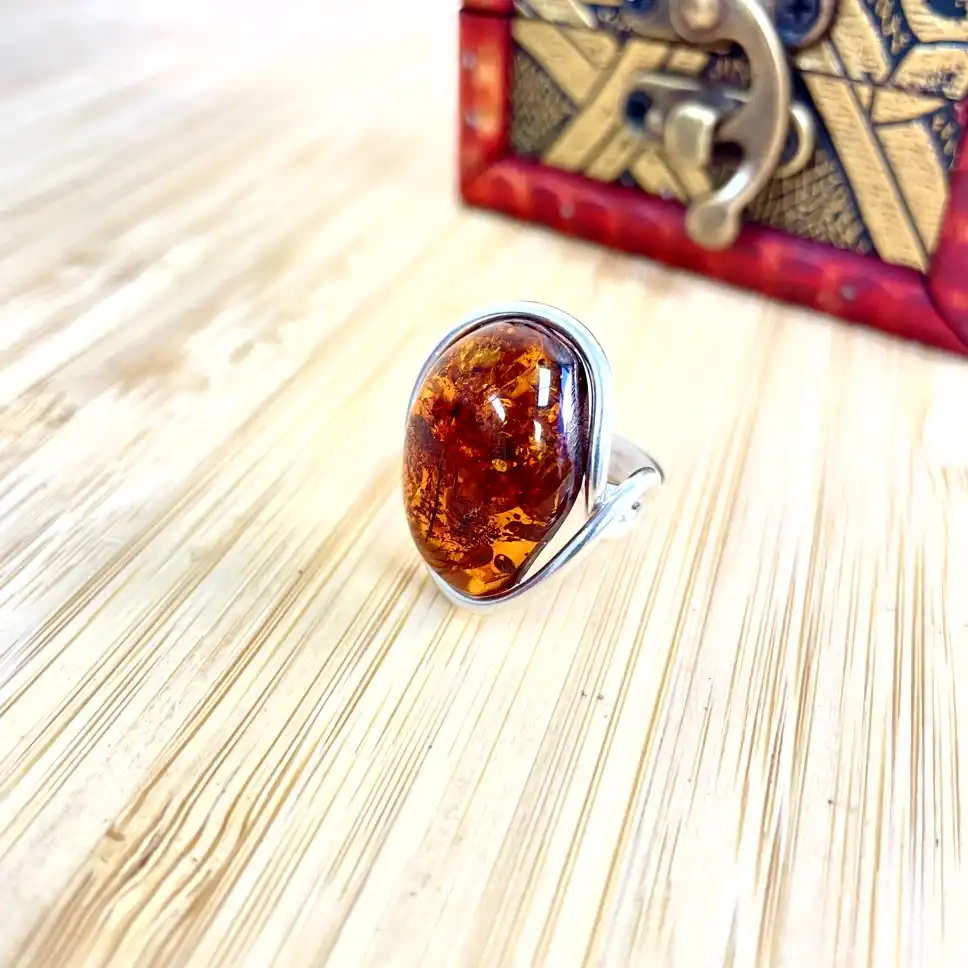 Elegant silver-plated amber ring in polished silver setting, showcasing a stunning oval cabochon.