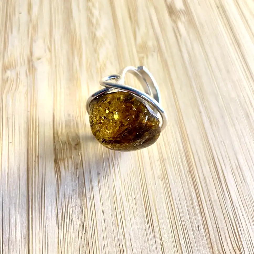 Stunning amber ring set in a silver band, showcasing intricate textures and a warm golden hue.