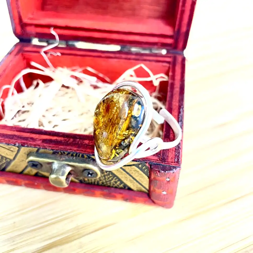 Elegant amber ring in vintage red box, showcasing natural inclusions and timeless beauty.
