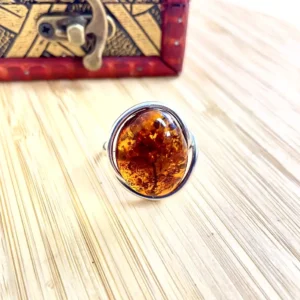 Stunning silver-plated amber ring with silver band, showcasing rich colors and organic inclusions, elegantly displayed.