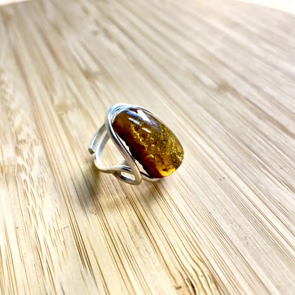 Stunning amber ring with a silver band, showcasing natural beauty on a wooden surface.