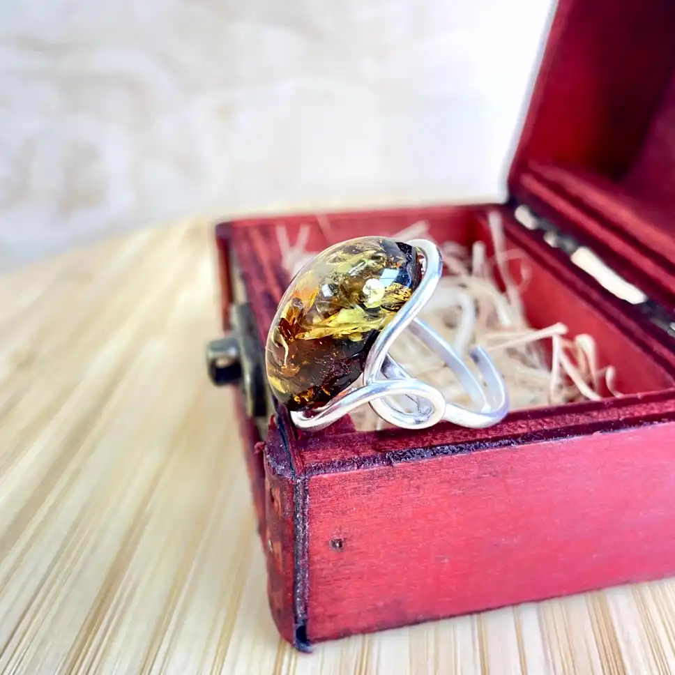 Exquisite silver-plated amber ring showcased in a vintage red wooden box, highlighting elegant craftsmanship.