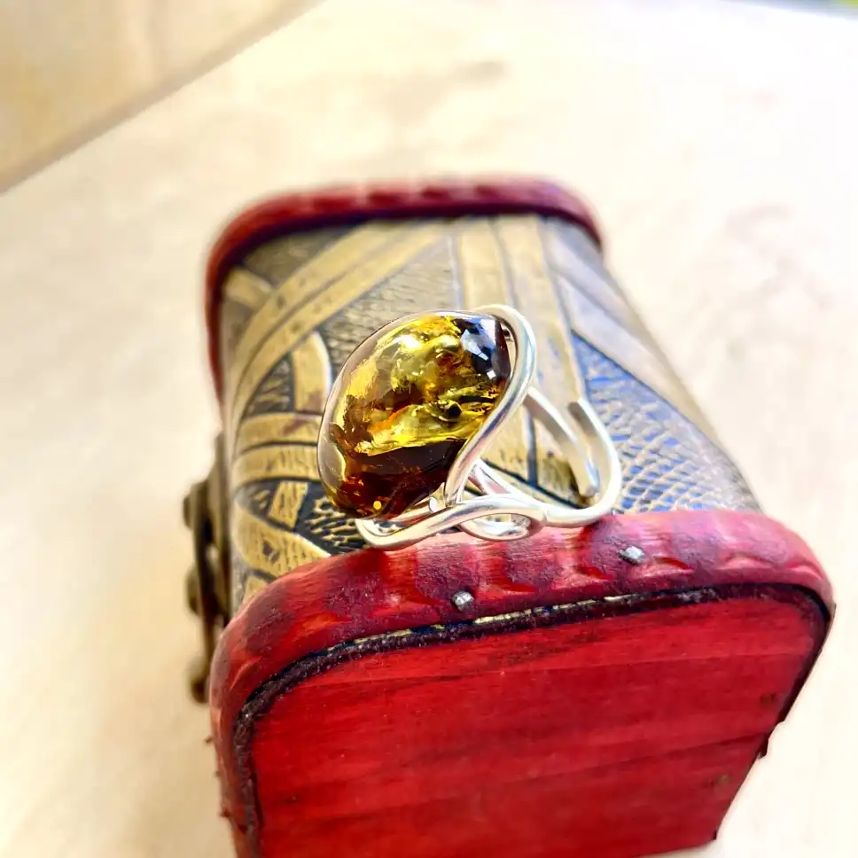 silver-plated Amber ring resting on a decorative wooden box, showcasing exquisite craftsmanship and rich colors.