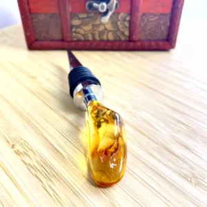 Unique amber bottle stopper with polished metal and rubber details on rustic wooden surface.