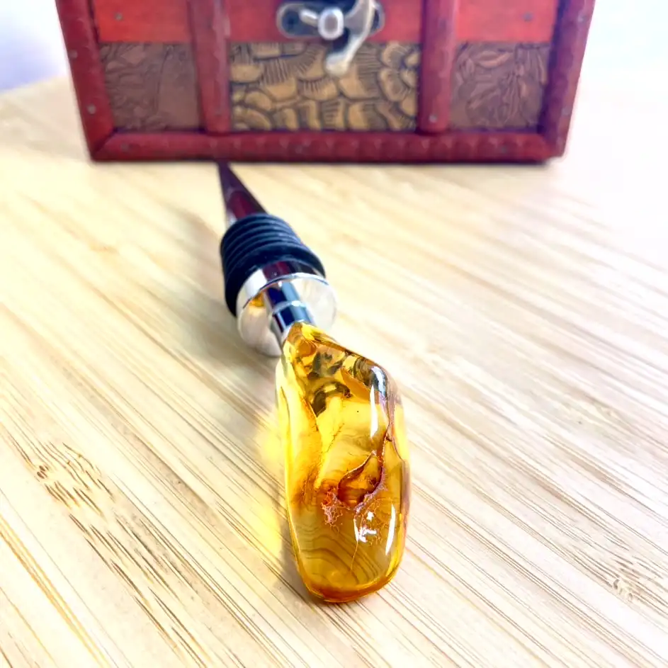 Unique amber bottle stopper with polished metal and rubber details on rustic wooden surface.