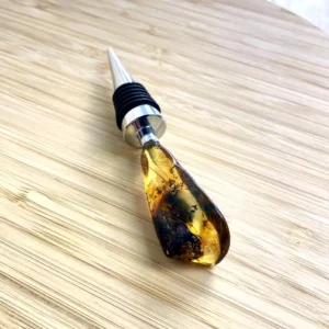 Elegant amber bottle stopper with silver-plated top, showcasing unique inclusions and natural beauty.