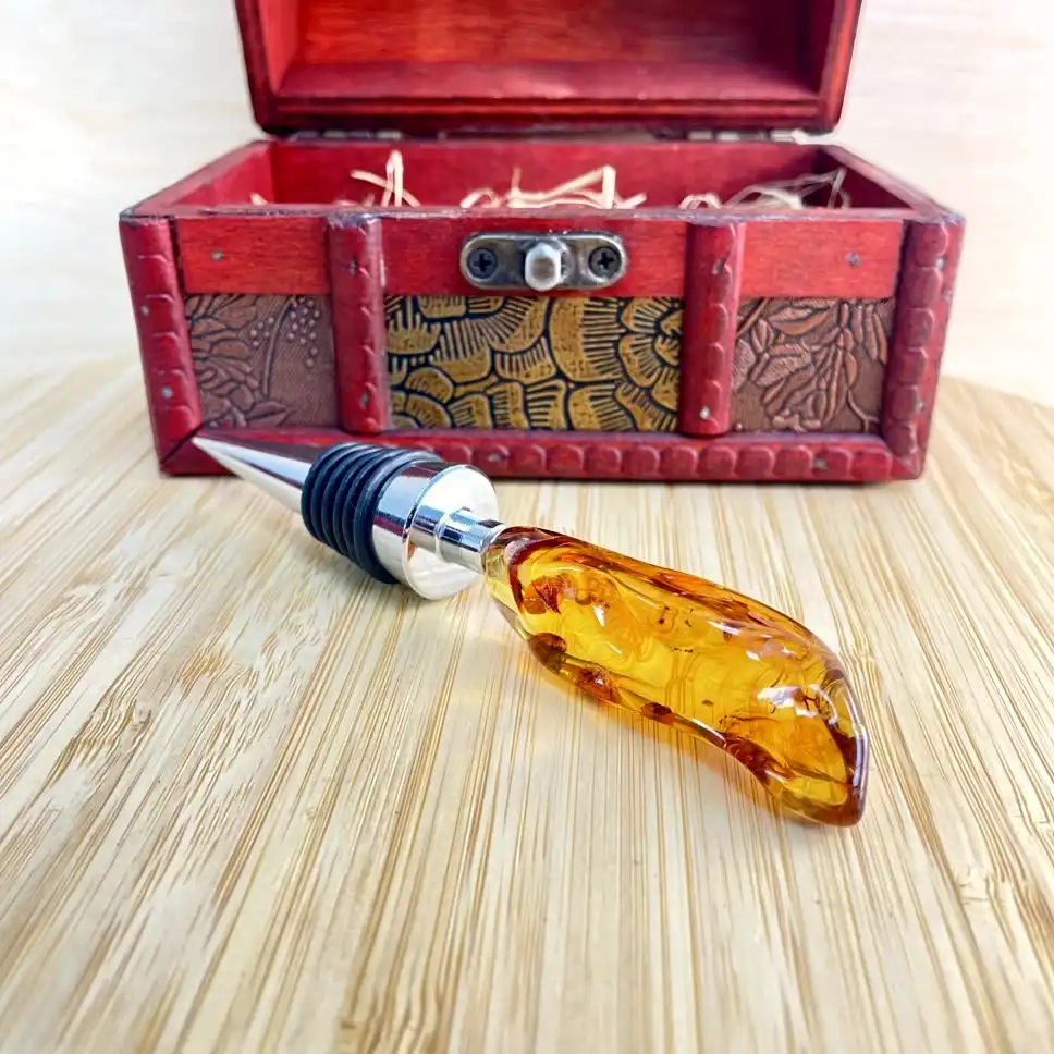 Elegant amber bottle stopper with intricate design beside a beautifully crafted wooden treasure chest.