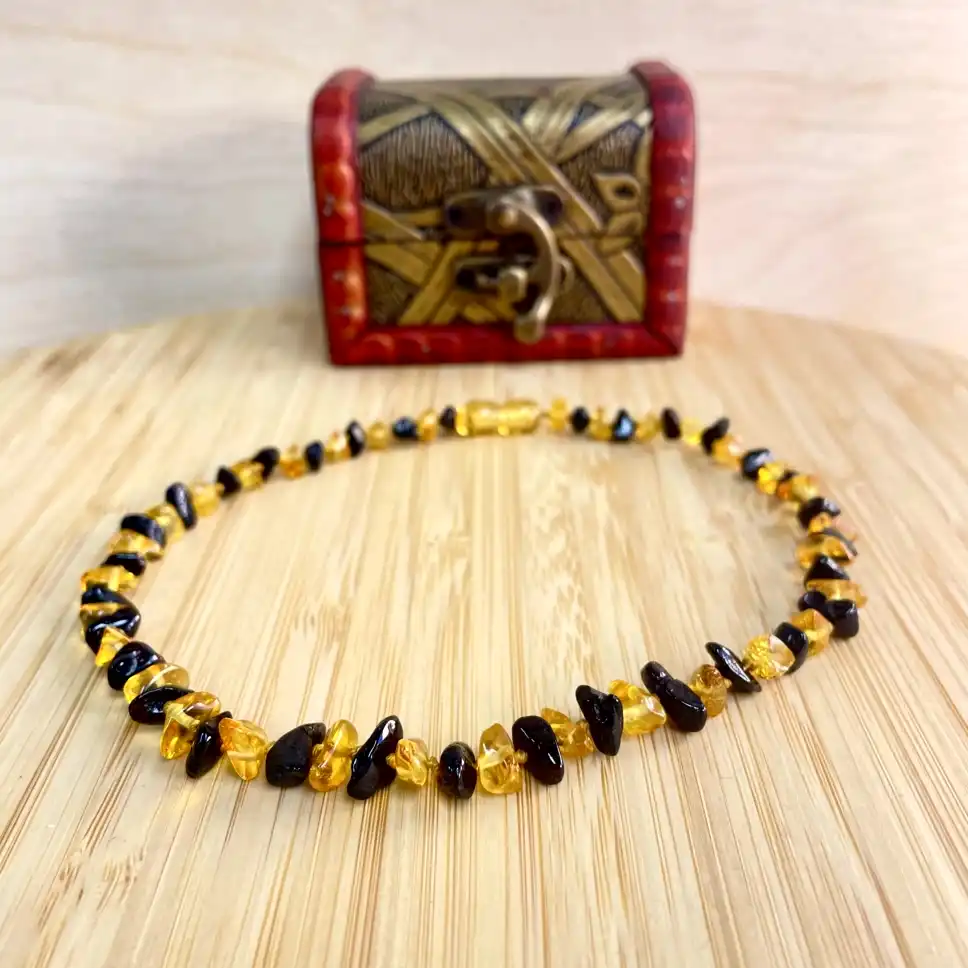 Elegant amber teething necklace with vintage treasure chest backdrop.
