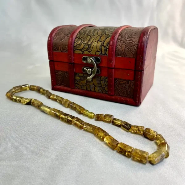 Antique red chest with golden accents and amber necklace, showcasing exquisite craftsmanship and elegance.