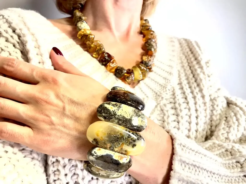 Elegant chunky amber jewelry paired with a cozy beige knitted sweater for a stylish look.