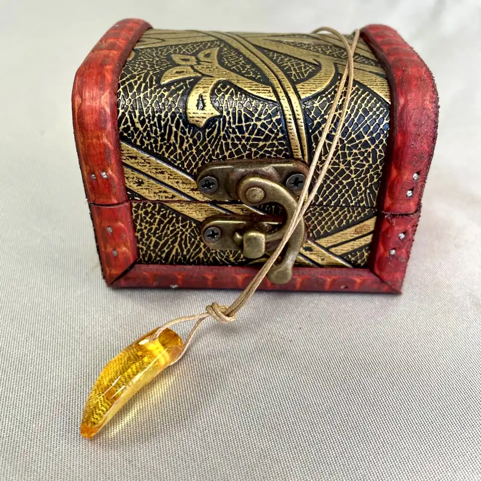 Intricately designed decorative chest with amber pendant, showcasing vintage charm and craftsmanship.