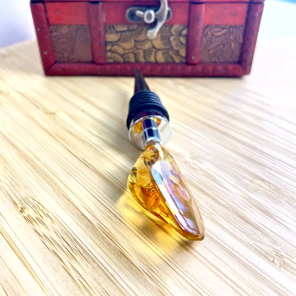 Elegant amber bottle stopper resting on wood, featuring a sleek design and practical rubber grip.
