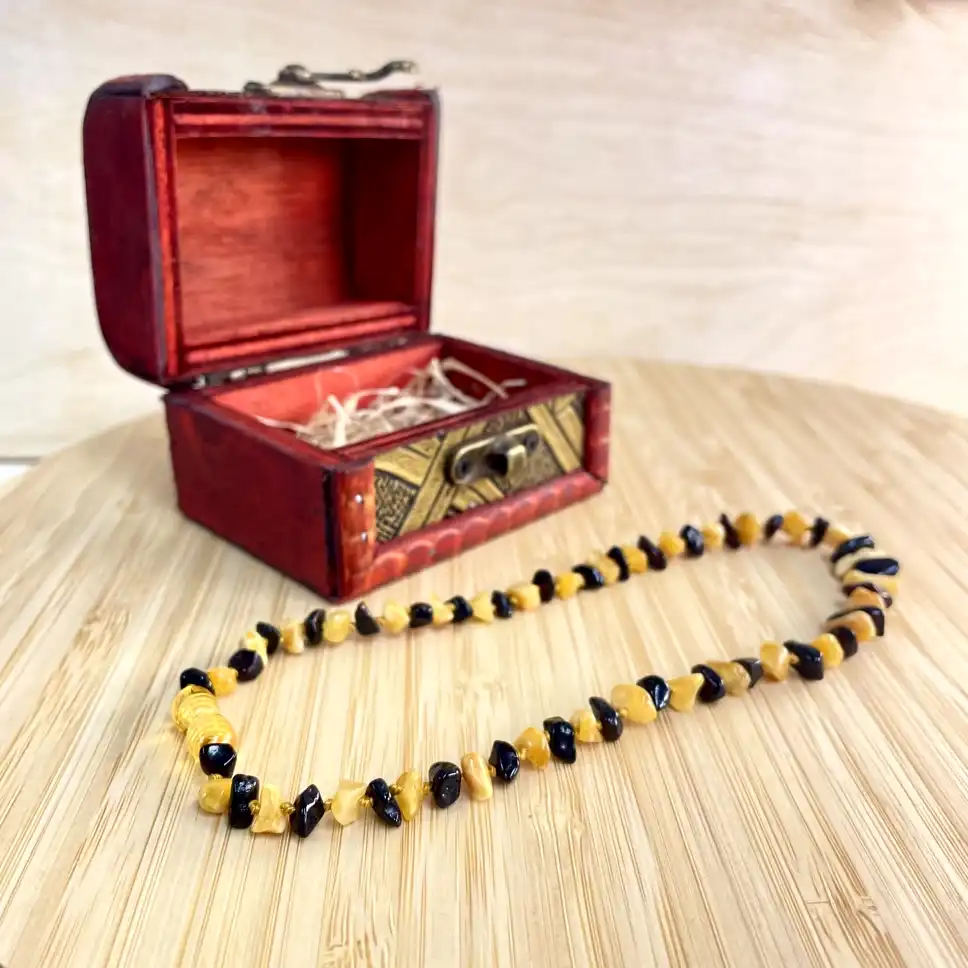 Elegant amber necklace in red jewelry box atop a warm wooden surface.