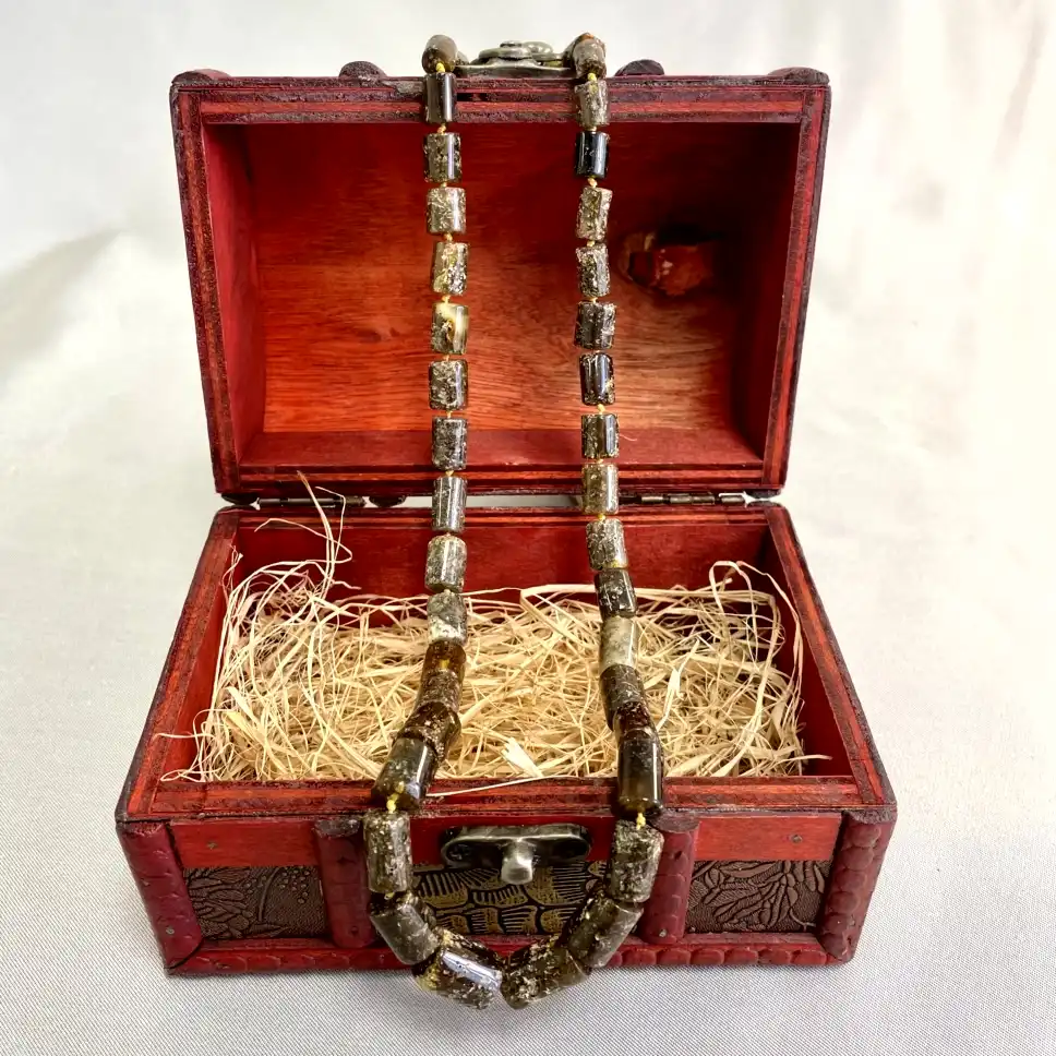 Beautiful red treasure chest with intricate carvings revealing a stunning beaded necklace inside.