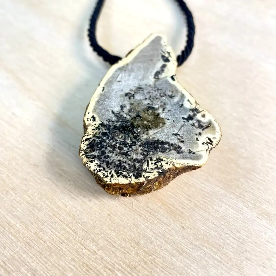 Natural amber chunk necklace with gold trim on a braided cord, showcasing unique textures and colors.