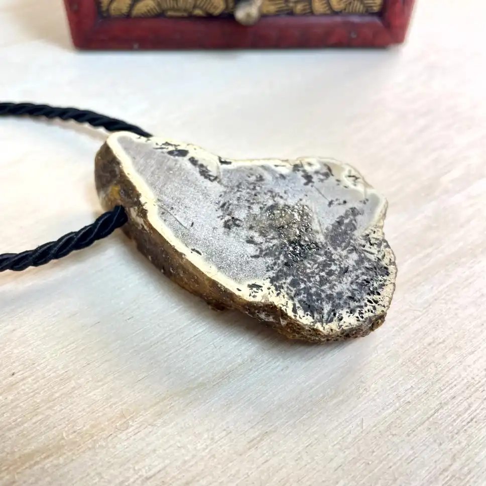 Natural amber chunk necklace with gold border on braided cord, showcasing unique textures and colors.