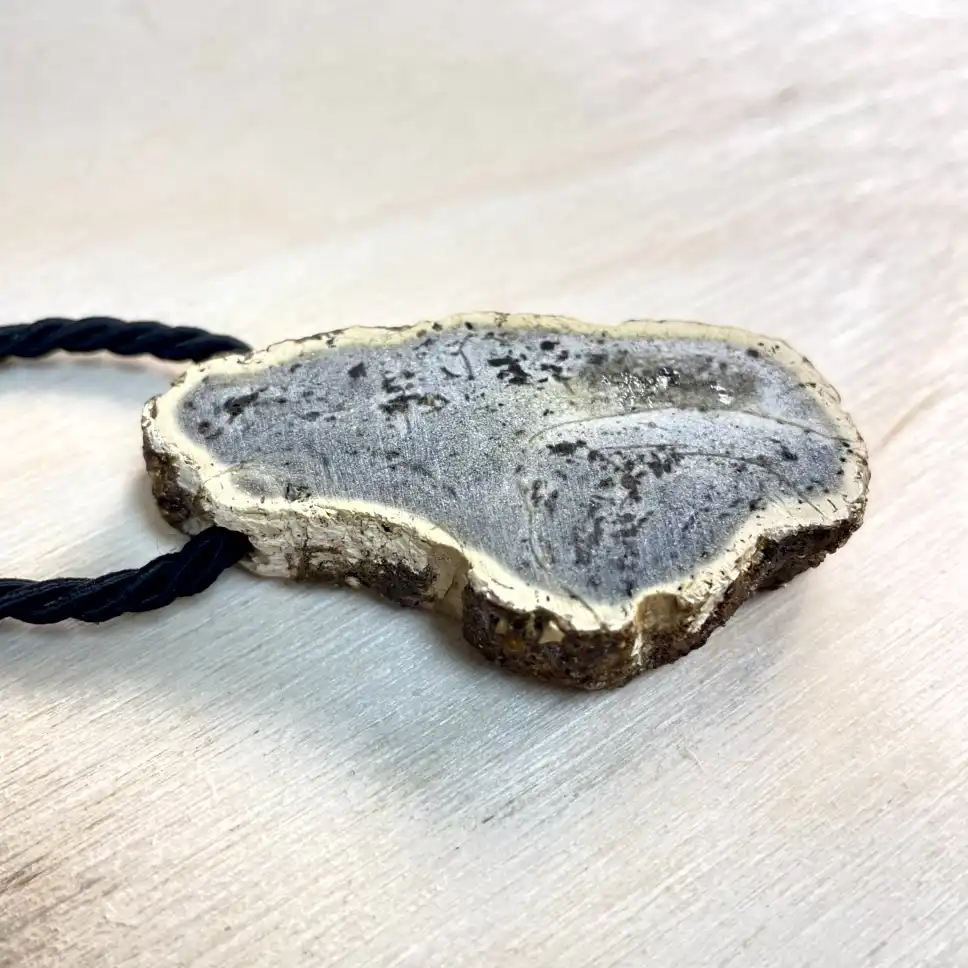 Unique amber chunk necklace with abstract design on a braided black cord.