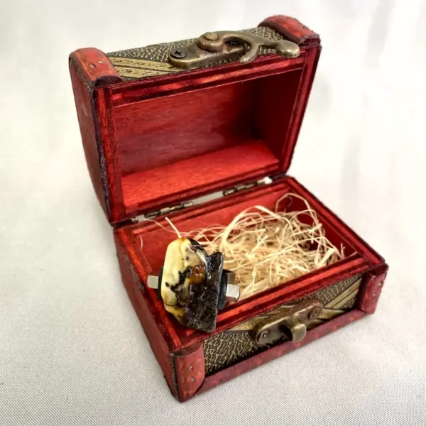Ornate antique jewelry box with vibrant red finish and stunning ring inside.