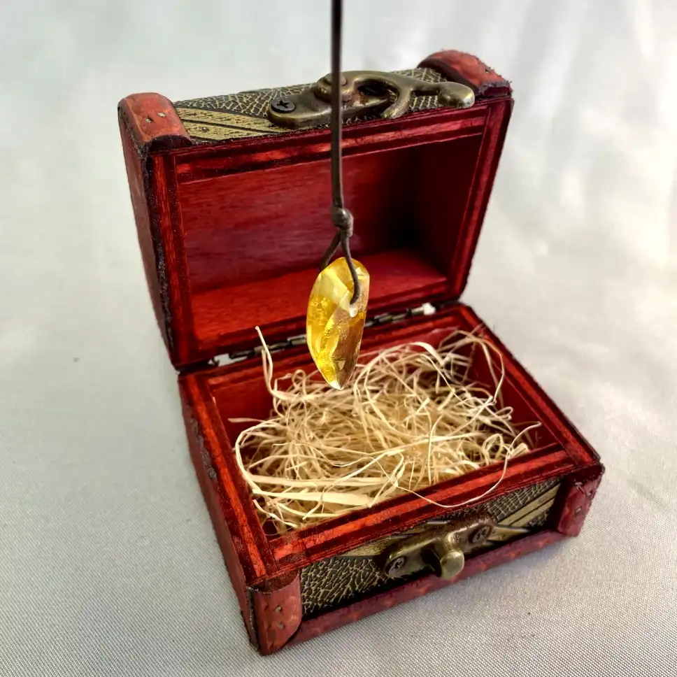 Ornate wooden treasure chest containing a stunning amber pendant, evoking curiosity and adventure.