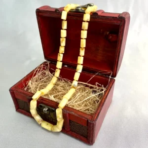 Ornate wooden treasure chest showcasing a unique yellow bead necklace, artistic craftsmanship, and vintage appeal.
