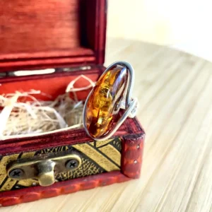 Elegant oval silver-plated amber ring in silver plating, displayed in a charming ornate jewelry box.