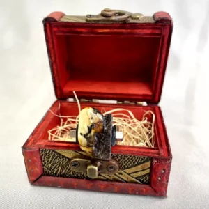 Ornate red jewelry box with amber artifact, combining vintage elegance and natural beauty.
