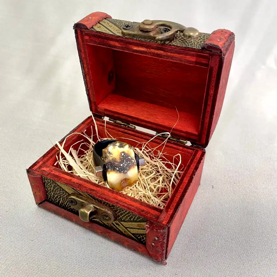 Ornate red wooden box with a striking ring and rustic straw cushioning inside.