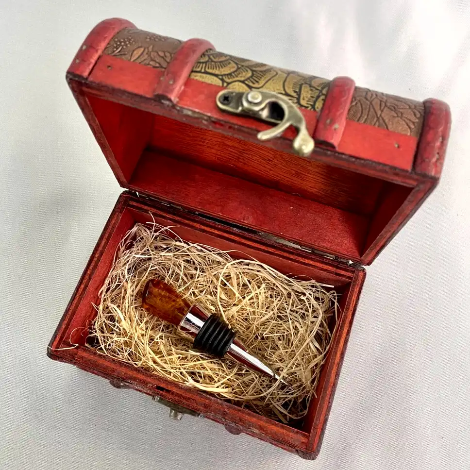 Elegant red wooden box with detailed gold artwork and a stylish wine bottle stopper inside.