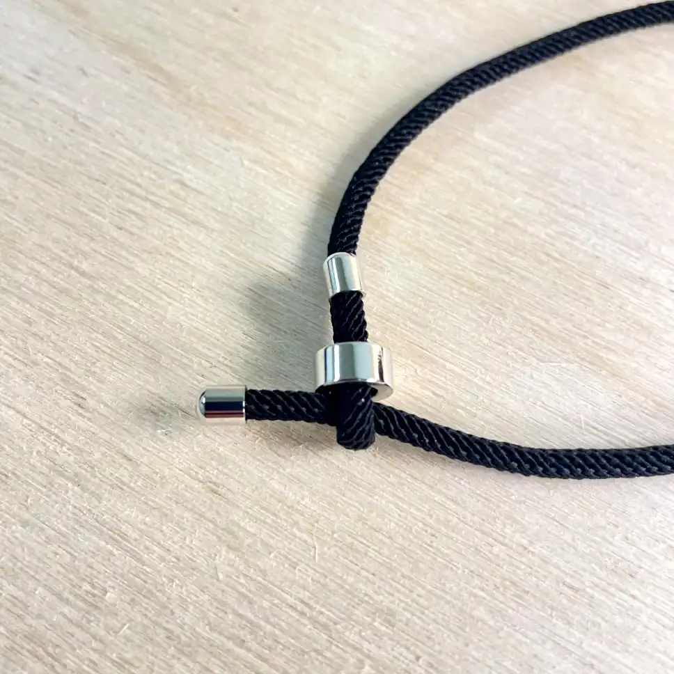 Stylish black cord necklace with polished amber metal clasp, blending elegance and modern design.