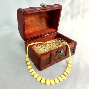 Antique wooden chest with a beautiful yellow bead necklace, showcasing vintage craftsmanship and charm.