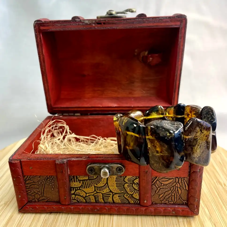 Vintage red treasure chest showcasing an exquisite amber bracelet, perfect for collectors and jewelry lovers.