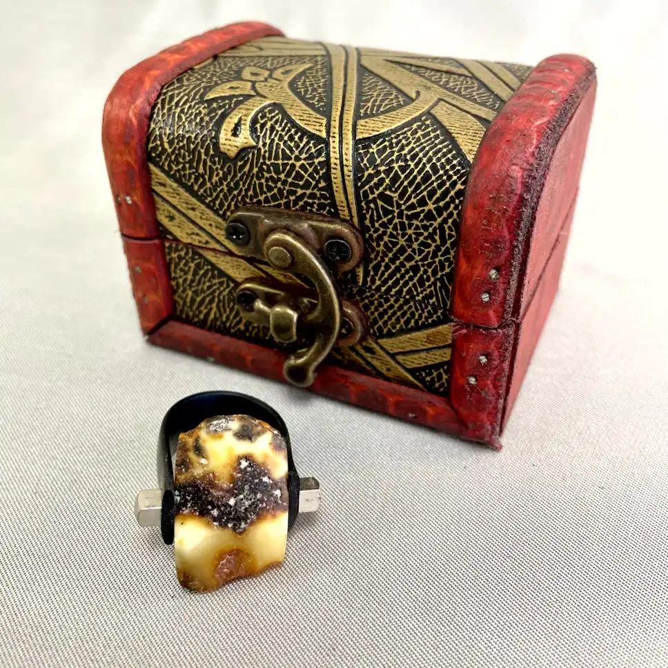 Antique treasure chest with ornate design alongside a modern black ring featuring colorful natural stone.