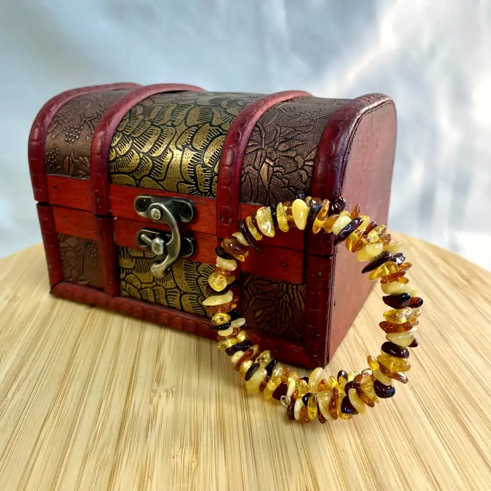 Vintage wooden treasure chest and amber bracelet, showcasing natural beauty and intricate craftsmanship.
