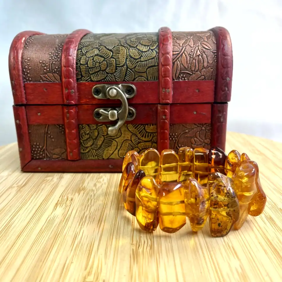 Vintage wooden treasure chest with ornate engravings and a stunning amber bracelet display.