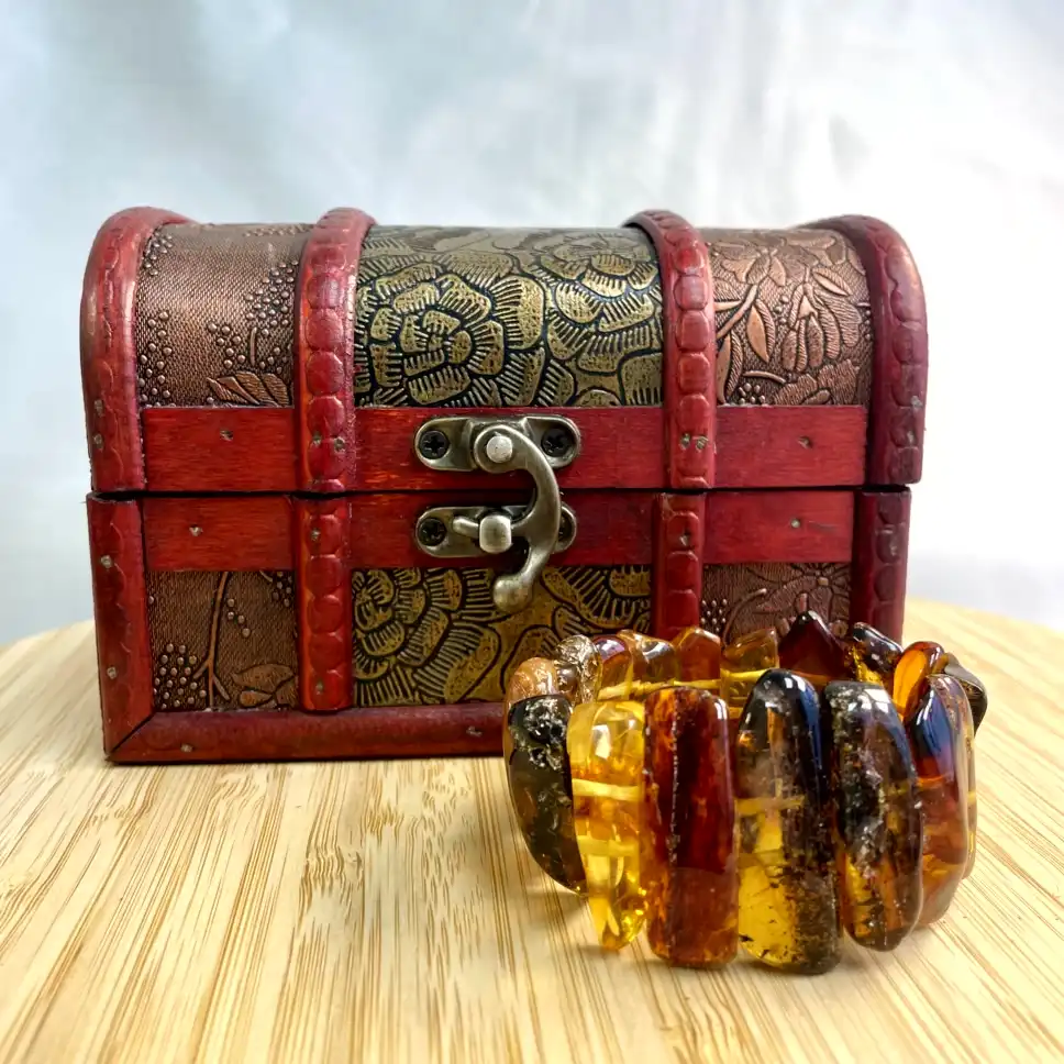 Elegant wooden treasure chest with a vintage design and a beautiful amber bracelet beside it.