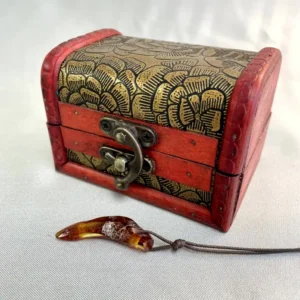 Vintage red wooden chest with gold detailing and amber pendant beside it.