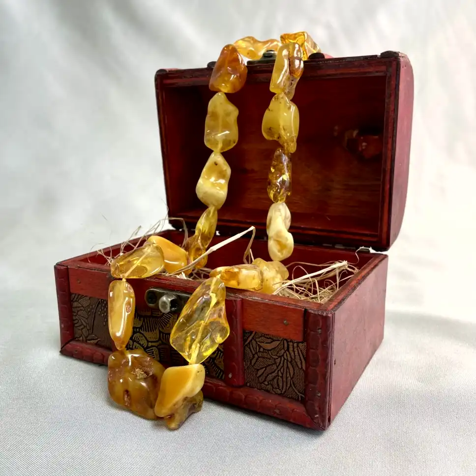 Ornate wooden chest showcasing a beautiful amber necklace, blending elegance and vintage charm.
