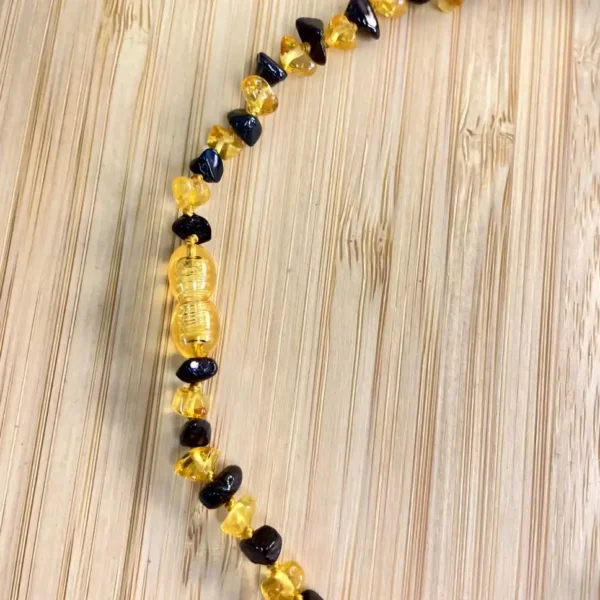 Amber and black bead necklace on wood, showcasing natures beauty and artisanal craftsmanship.