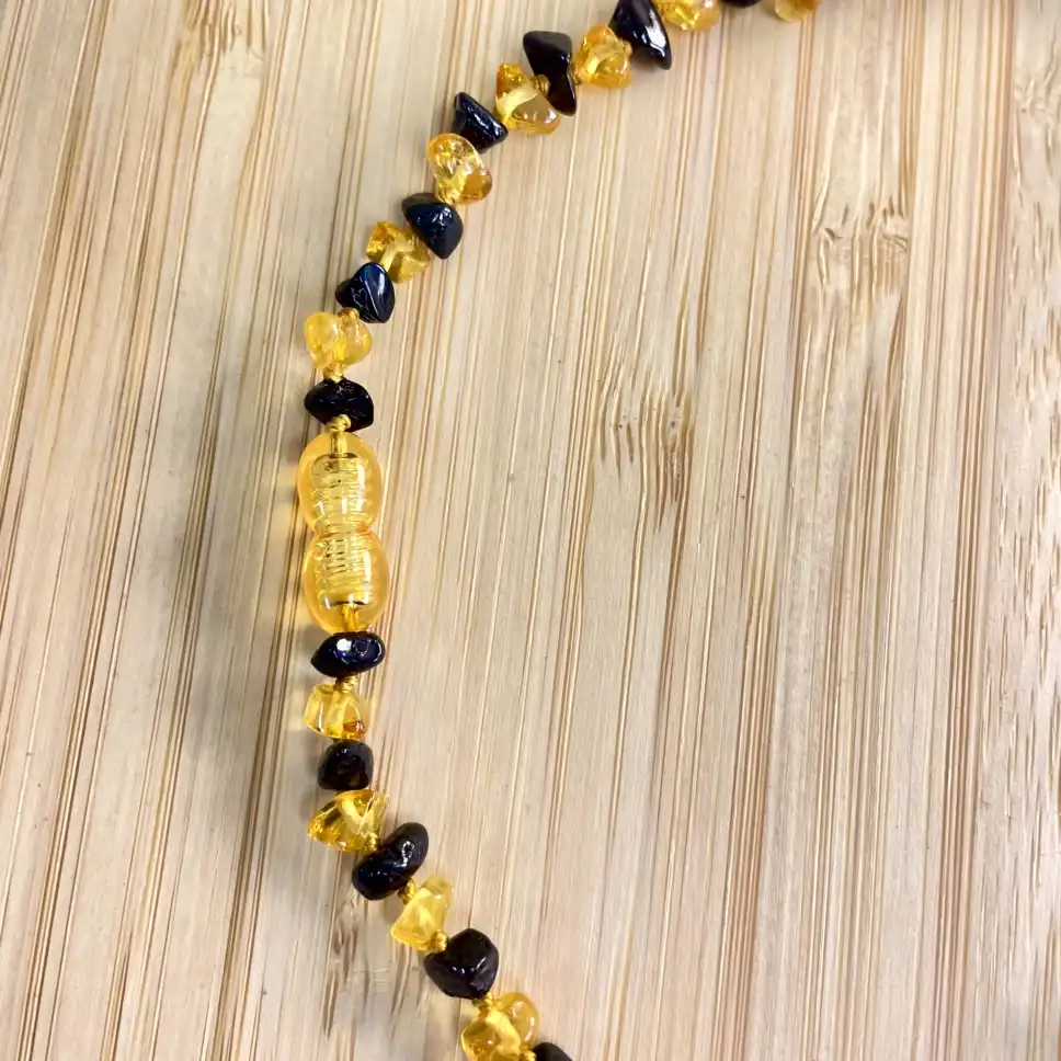 Amber and black bead necklace on wood, showcasing natures beauty and artisanal craftsmanship.